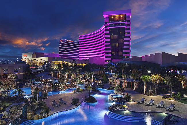 Choctaw Casino & Resort Durant location at dusk, purple-lit hotel towers overlooking illuminated pools, cabanas, and palm trees
