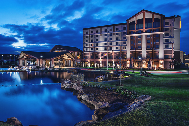 Choctaw Casino – Pocola exterior view with entrance and illuminated signage overlooking a pond