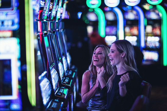 Two happy women playing slots and cheering