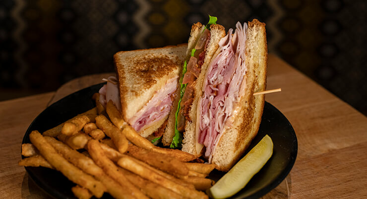 Club sandwich with fries and a pickle