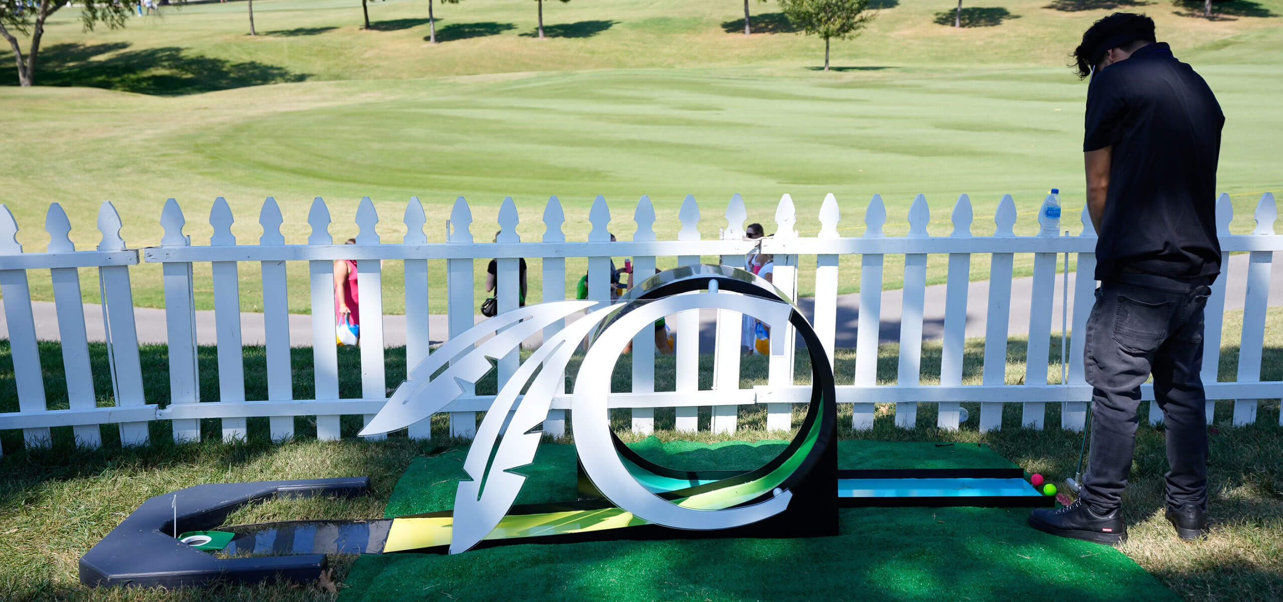 Artful golf-themed ‘putting loop’ installation with a curved metal arch framing a short putting lane