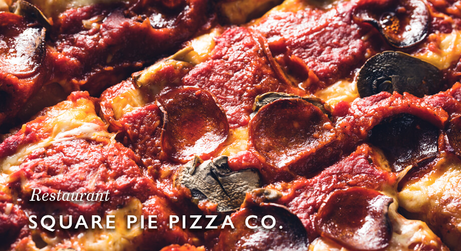 Close-up of Square Pie Pizza Co pizza pan with pepperoni, mushrooms, and red sauce