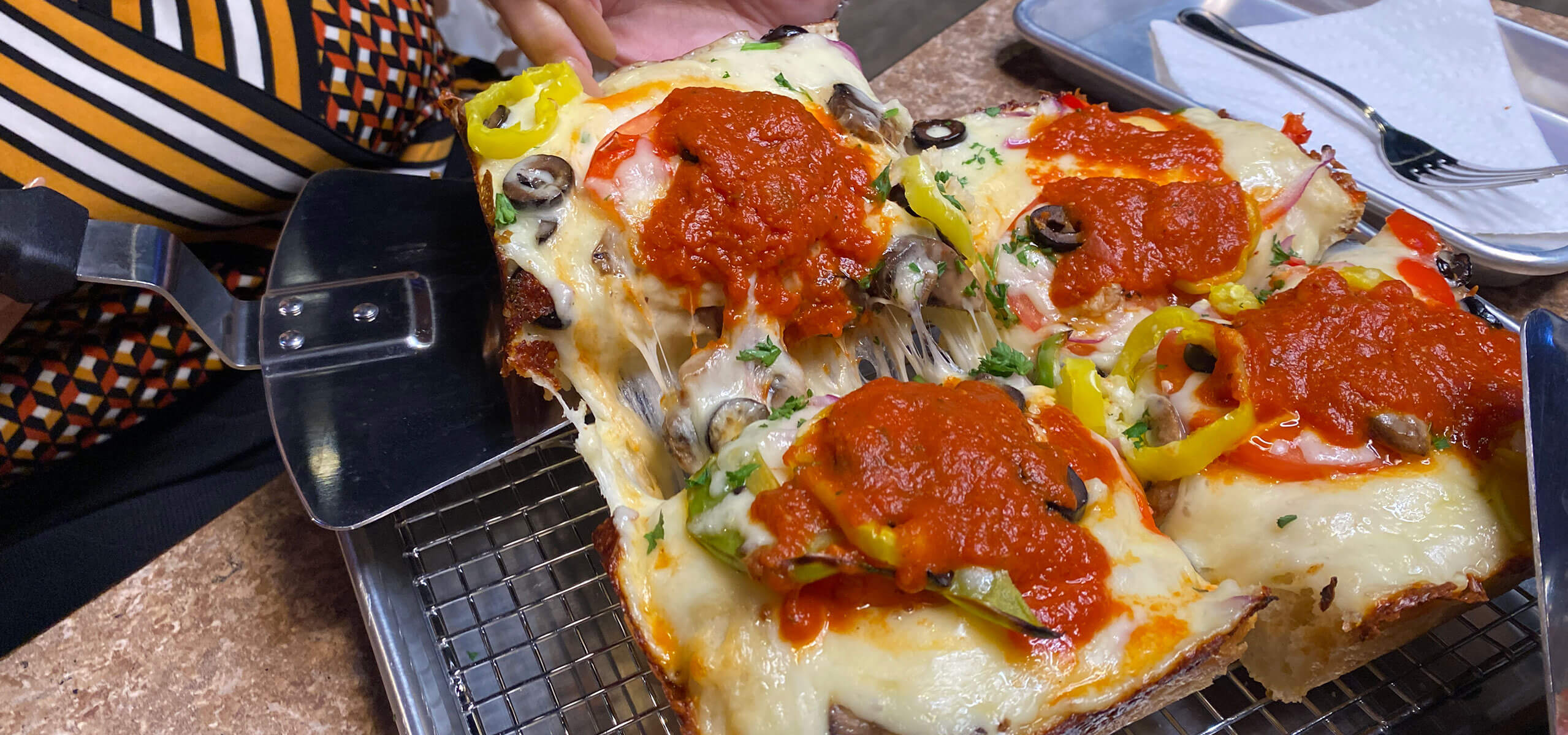 Square Pie Pizza Co. pan pizza with thick crust topped with pepperoni, mushrooms, and ladled red sauce.