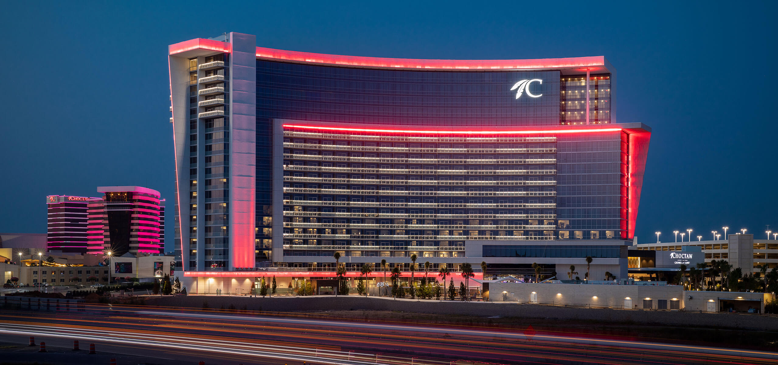 Choctaw Casino & Resort – Durant exterior at night with pink neon outlines and light trails from passing traffic