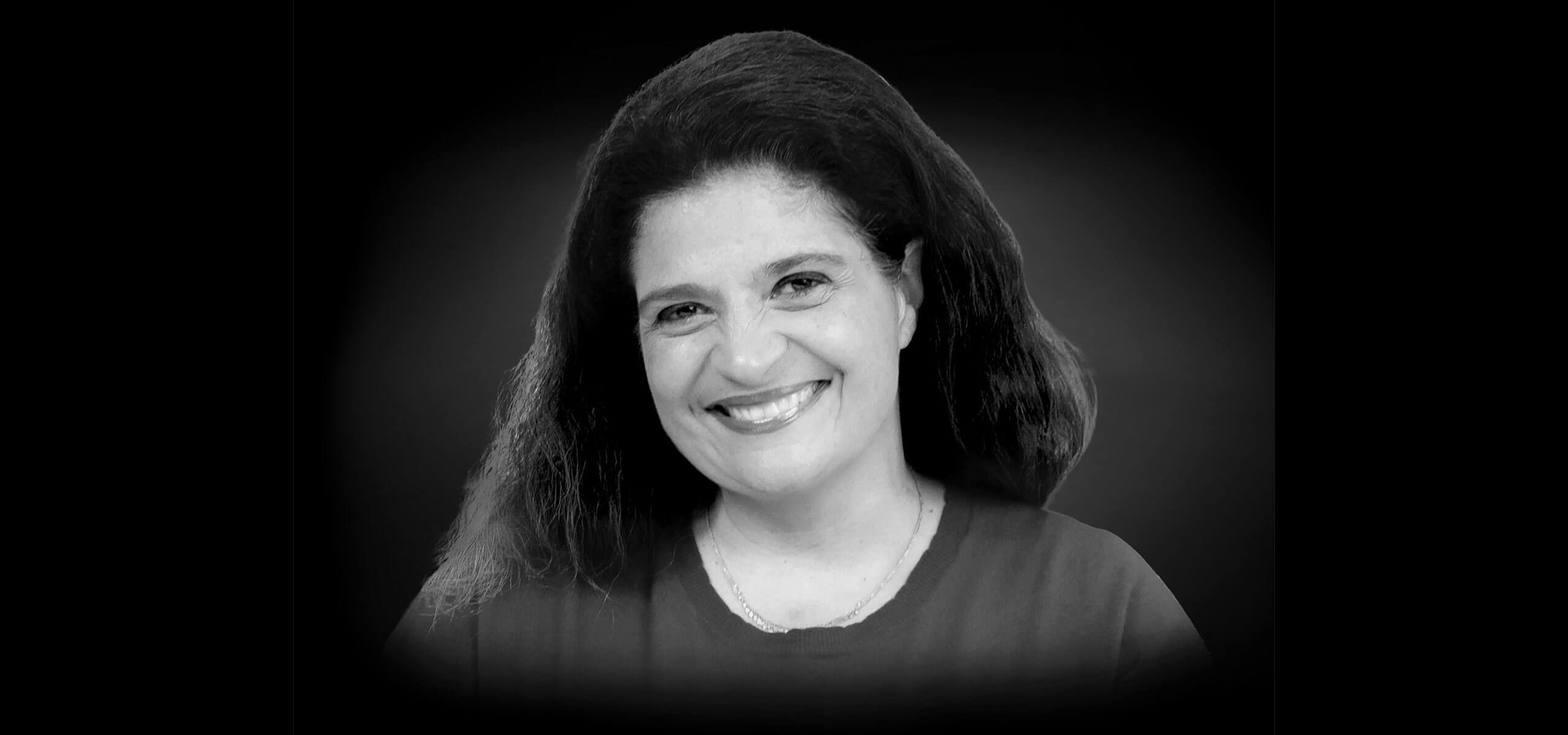 Black-and-white headshot of Alex Guarnaschelli smiling against a dark vignette background