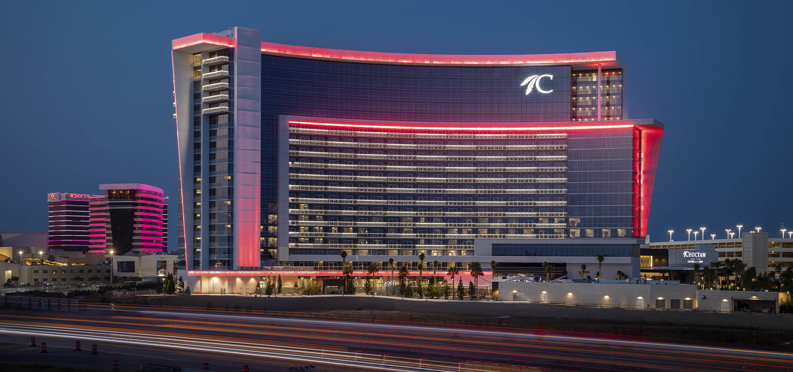 Choctaw Casino & Resort – Durant exterior at dusk with pink neon trim and traffic light trails in front
